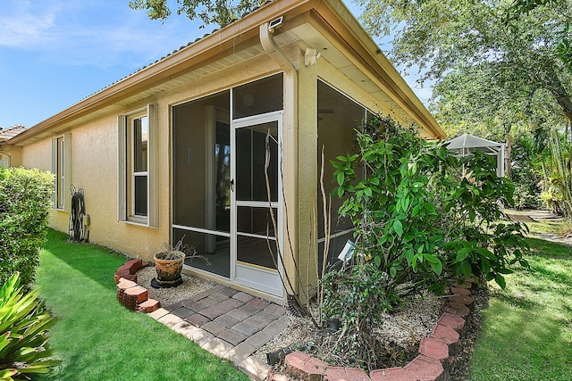 3611 NW Willow Creek Dr, Jensen Beach, FL 34957 - view of side of property featuring stucco siding, a sunroom, and a yard