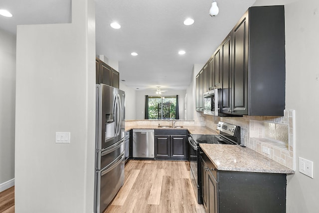 3611 NW Willow Creek Dr, Jensen Beach, FL 34957 - kitchen with appliances with stainless steel finishes, light wood finished floors, tasteful backsplash, light stone countertops, and a ceiling fan