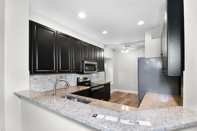 3611 NW Willow Creek Dr, Jensen Beach, FL 34957 - kitchen with appliances with stainless steel finishes, dark cabinetry, light wood-style flooring, backsplash, and a ceiling fan