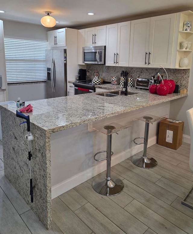 21404 Cypress Hammock Dr Unit 45E, Boca Raton, FL 33428 - kitchen with stainless steel appliances, open shelves, a peninsula, light stone countertops, and light wood-type flooring