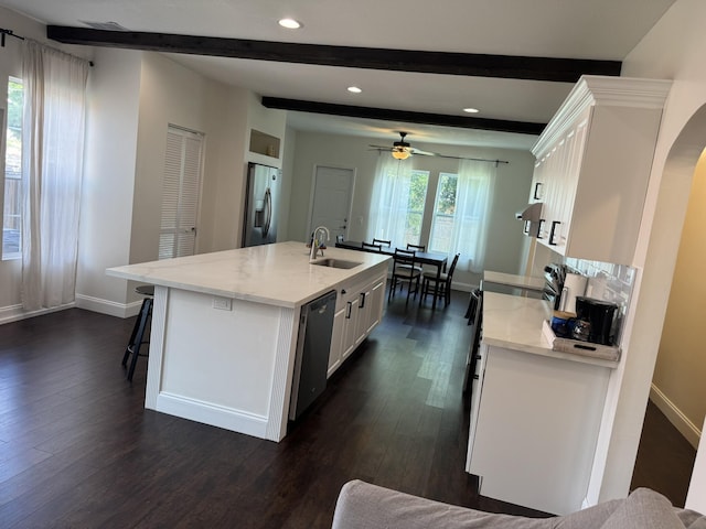 639 38th St, West Palm Beach, FL 33407 - kitchen featuring stainless steel appliances, beam ceiling, dark wood-style floors, white cabinetry, and a center island with sink