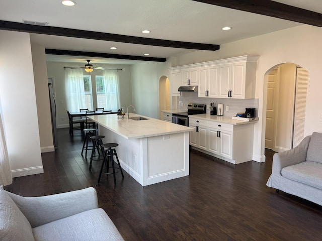 639 38th St, West Palm Beach, FL 33407 - kitchen featuring arched walkways, electric range, beamed ceiling, under cabinet range hood, and dark wood-type flooring