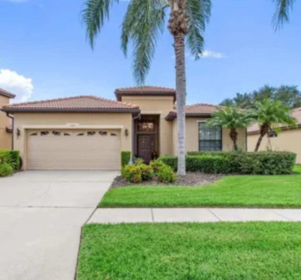 128 Silver Falls Dr, Apollo Beach, FL 33572 - mediterranean / spanish-style home with a garage, stucco siding, concrete driveway, a front lawn, and a tiled roof