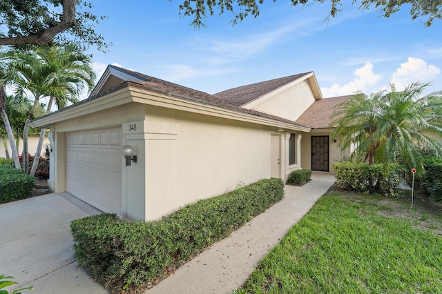 348 River Edge Rd, Jupiter, FL 33477 - view of side of home featuring stucco siding, a garage, driveway, and a shingled roof