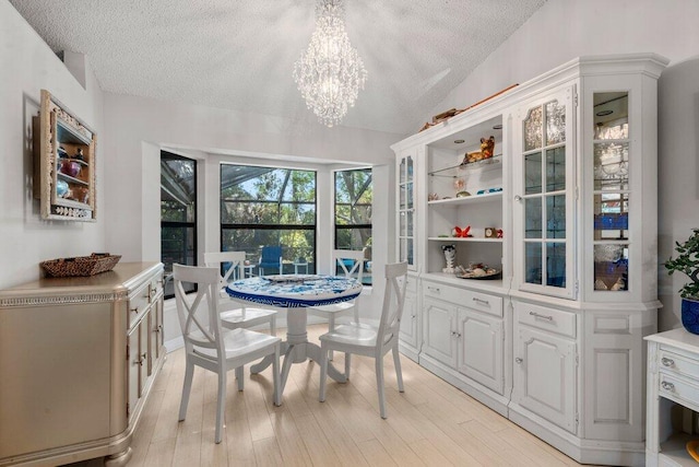 2997 SW Collings Dr, Port Saint Lucie, FL 34953 - dining area featuring a textured ceiling, a chandelier, light wood-type flooring, and vaulted ceiling