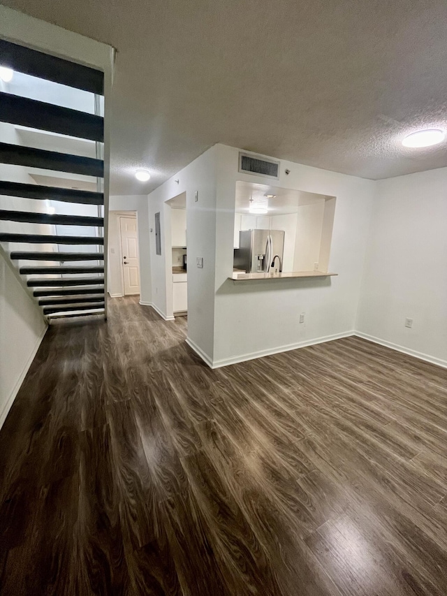 1100 Scotia Dr Unit 102, Hypoluxo, FL 33462 - unfurnished living room featuring dark wood-style floors, a textured ceiling, and stairs