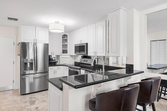 1219 Ocean Dunes Cir, Jupiter, FL 33477 - kitchen with appliances with stainless steel finishes, a peninsula, a kitchen breakfast bar, glass insert cabinets, and white cabinets