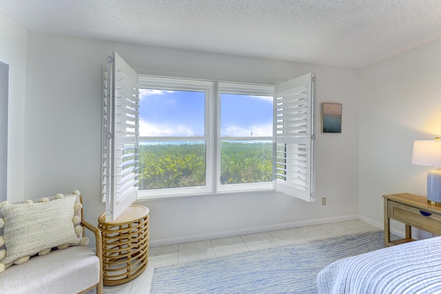 2571 NE Ocean Blvd Unit 104, Stuart, FL 34996 - tiled bedroom featuring a textured ceiling and baseboards