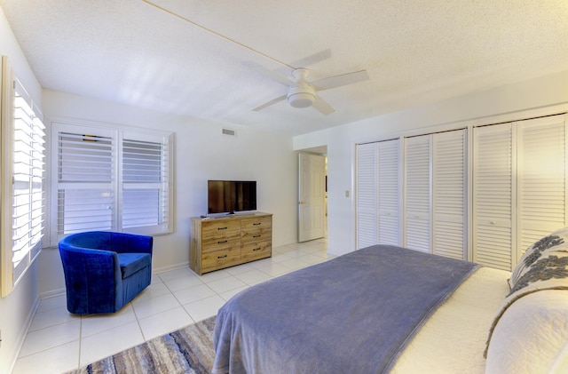 2571 NE Ocean Blvd Unit 104, Stuart, FL 34996 - tiled bedroom featuring multiple closets, a textured ceiling, and a ceiling fan