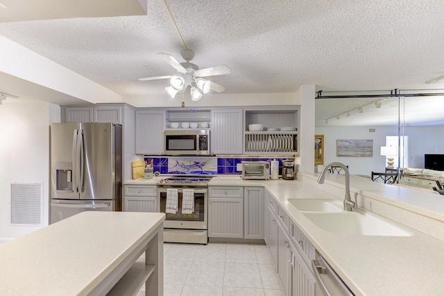 2571 NE Ocean Blvd Unit 104, Stuart, FL 34996 - kitchen featuring appliances with stainless steel finishes, open shelves, light countertops, gray cabinetry, and light tile patterned floors