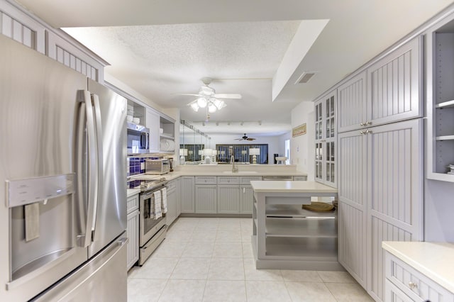 2571 NE Ocean Blvd Unit 104, Stuart, FL 34996 - kitchen with appliances with stainless steel finishes, ceiling fan, light countertops, light tile patterned floors, and glass insert cabinets