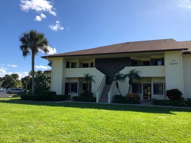6303 SE Williamsburg Dr Unit 201, Hobe Sound, FL 33455 - rear view of property featuring a lawn, stucco siding, and stairway