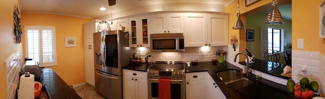 6303 SE Williamsburg Dr Unit 201, Hobe Sound, FL 33455 - kitchen featuring stainless steel appliances, healthy amount of natural light, glass insert cabinets, hanging light fixtures, and crown molding