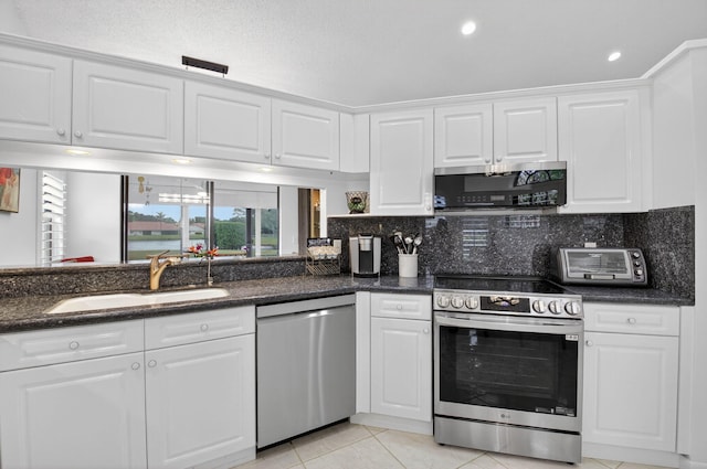 7585 Lexington Club Blvd Unit A, Delray Beach, FL 33446 - kitchen with appliances with stainless steel finishes, white cabinets, light tile patterned floors, and tasteful backsplash