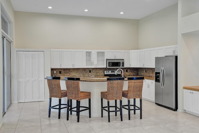 6809 Portside Dr, Boca Raton, FL 33496 - kitchen with stainless steel appliances, a high ceiling, a kitchen island with sink, backsplash, and light tile patterned flooring