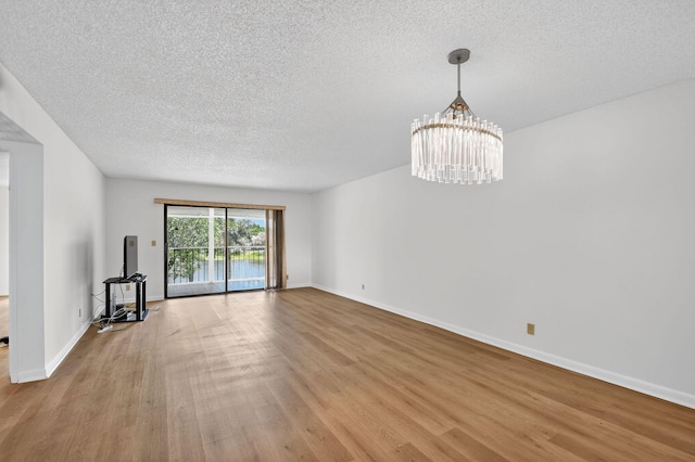 7290 Ashford Pl Unit 201, Delray Beach, FL 33446 - unfurnished living room featuring a textured ceiling, light wood-style flooring, and a chandelier