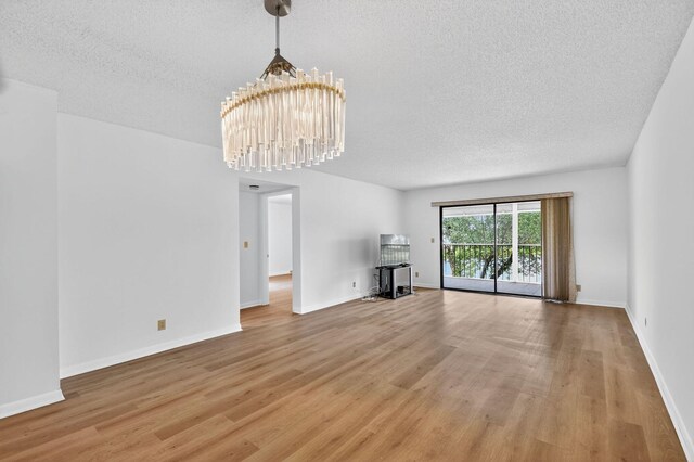 7290 Ashford Pl Unit 201, Delray Beach, FL 33446 - unfurnished living room featuring light wood-style floors, a chandelier, and a textured ceiling