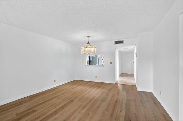 7290 Ashford Pl Unit 201, Delray Beach, FL 33446 - unfurnished room featuring light wood-type flooring, a chandelier, and a textured ceiling