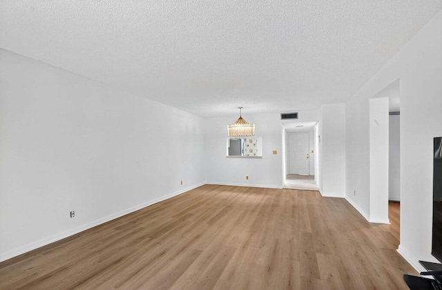 7290 Ashford Pl Unit 201, Delray Beach, FL 33446 - unfurnished living room featuring light wood-style floors, a textured ceiling, and a chandelier