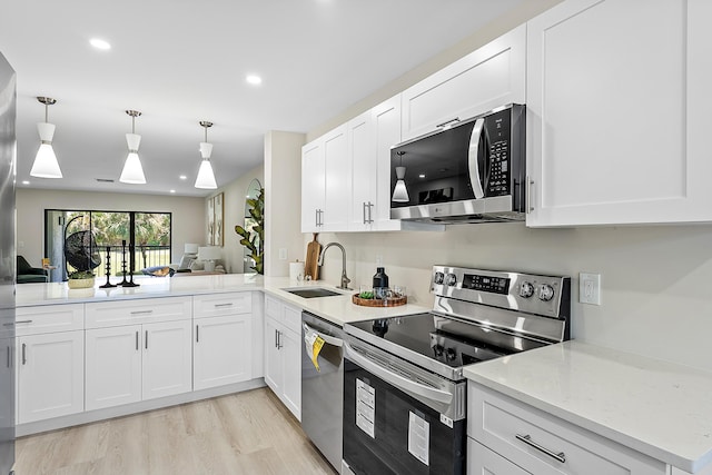 20 Southport Ln Unit D, Boynton Beach, FL 33436 - kitchen featuring appliances with stainless steel finishes, white cabinets, light wood-style floors, recessed lighting, and light stone counters