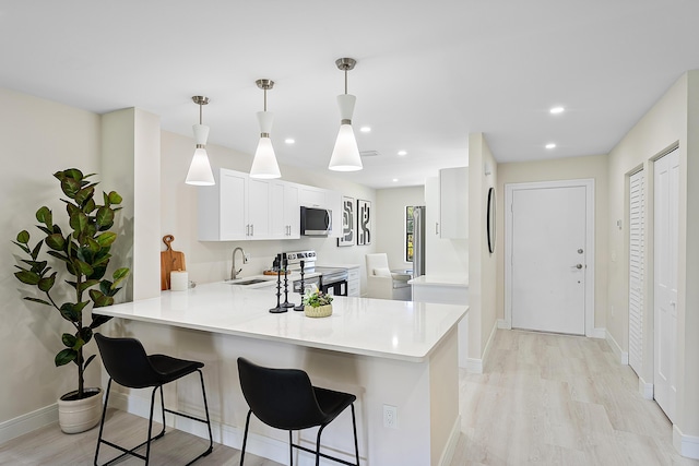 20 Southport Ln Unit D, Boynton Beach, FL 33436 - kitchen featuring stainless steel appliances, a peninsula, a breakfast bar, light countertops, and light wood-type flooring