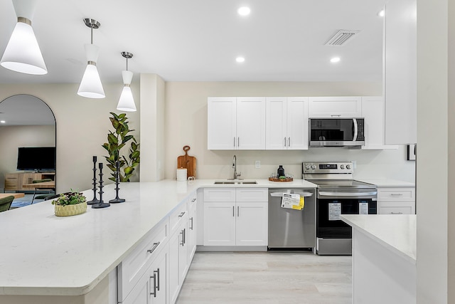 20 Southport Ln Unit D, Boynton Beach, FL 33436 - kitchen with stainless steel appliances, a peninsula, white cabinets, recessed lighting, and light wood finished floors