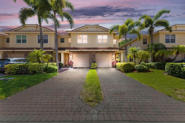 9482 SW Purple Martin Way, Stuart, FL 34997 - townhome / multi-family property with stucco siding, decorative driveway, a garage, stone siding, and a yard