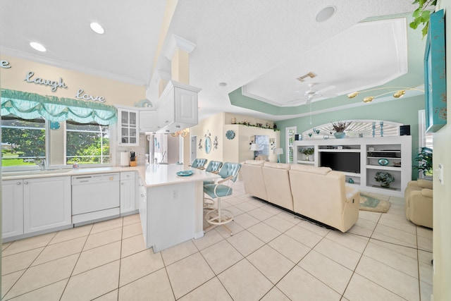 1104 SE Strathmore Dr, Port Saint Lucie, FL 34952 - kitchen with dishwasher, open floor plan, a kitchen breakfast bar, light tile patterned floors, and white cabinets