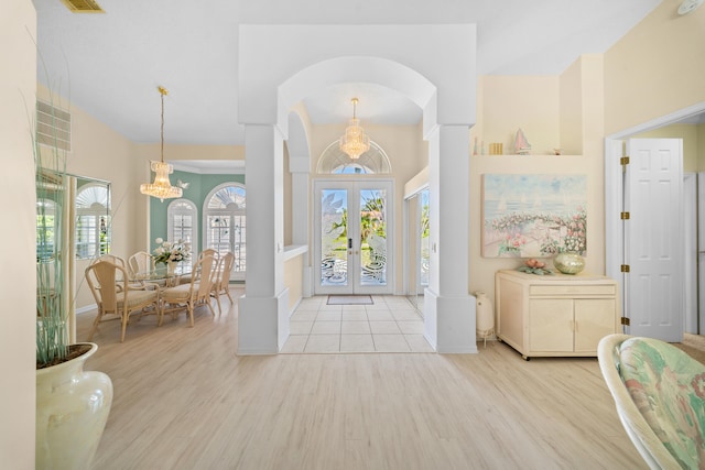 1104 SE Strathmore Dr, Port Saint Lucie, FL 34952 - foyer entrance with french doors, wood finished floors, arched walkways, and a chandelier