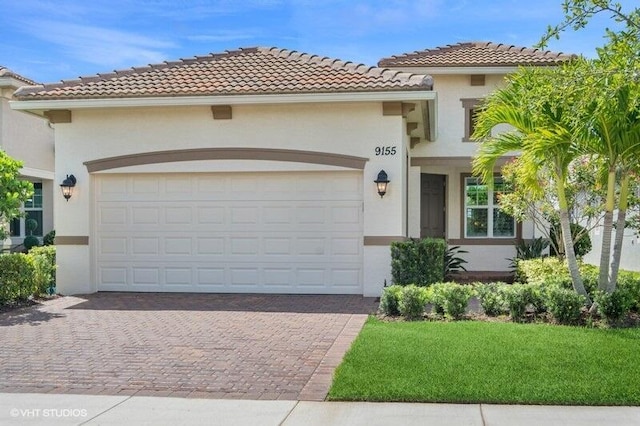 9155 SW Michele Way, Port Saint Lucie, FL 34987 - mediterranean / spanish house with stucco siding, decorative driveway, a tile roof, a front lawn, and a garage