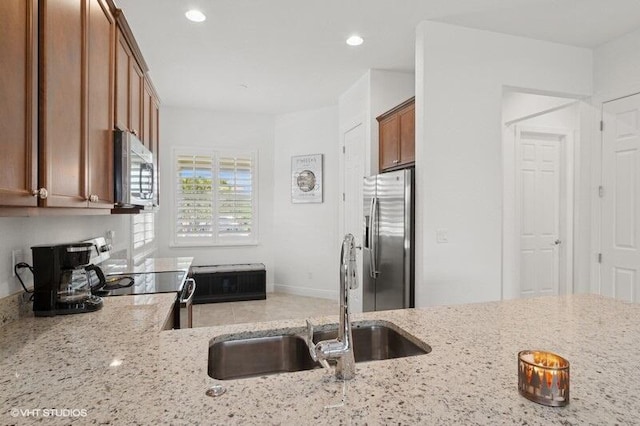 9155 SW Michele Way, Port Saint Lucie, FL 34987 - kitchen with appliances with stainless steel finishes, brown cabinets, light stone counters, and recessed lighting