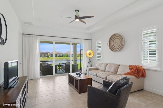9155 SW Michele Way, Port Saint Lucie, FL 34987 - living room with a ceiling fan, a tray ceiling, light tile patterned flooring, and a water view
