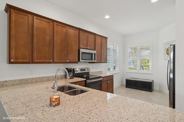 9155 SW Michele Way, Port Saint Lucie, FL 34987 - kitchen featuring appliances with stainless steel finishes, light stone counters, recessed lighting, brown cabinets, and light tile patterned floors