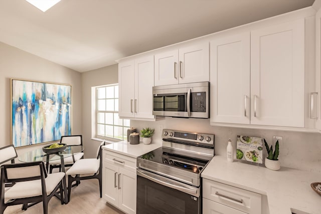 8008 Red Reef Ln, Boynton Beach, FL 33436 - kitchen featuring appliances with stainless steel finishes, light countertops, white cabinets, and lofted ceiling