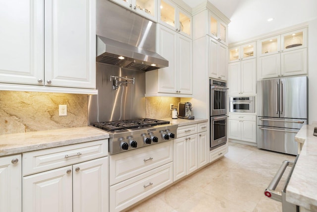 216 Summa St, West Palm Beach, FL 33405 - kitchen with appliances with stainless steel finishes, range hood, light stone counters, and white cabinetry