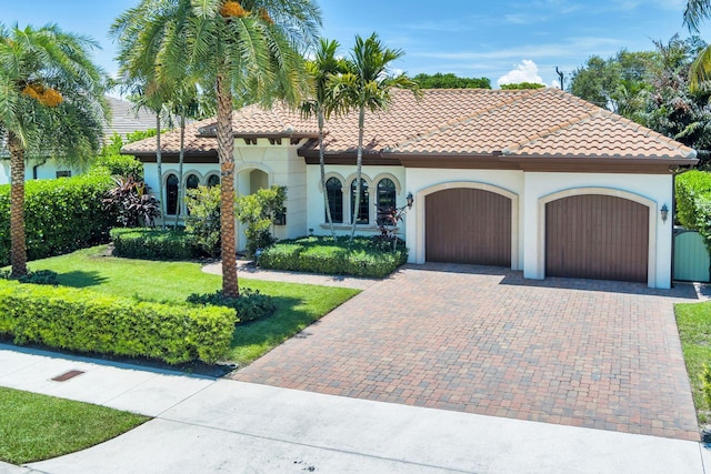 216 Summa St, West Palm Beach, FL 33405 - mediterranean / spanish home featuring a garage, decorative driveway, a front lawn, stucco siding, and a tiled roof