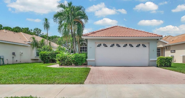 511 SW Treasure Cv, Port Saint Lucie, FL 34986 - mediterranean / spanish-style house with decorative driveway, a front lawn, stucco siding, a tiled roof, and an attached garage