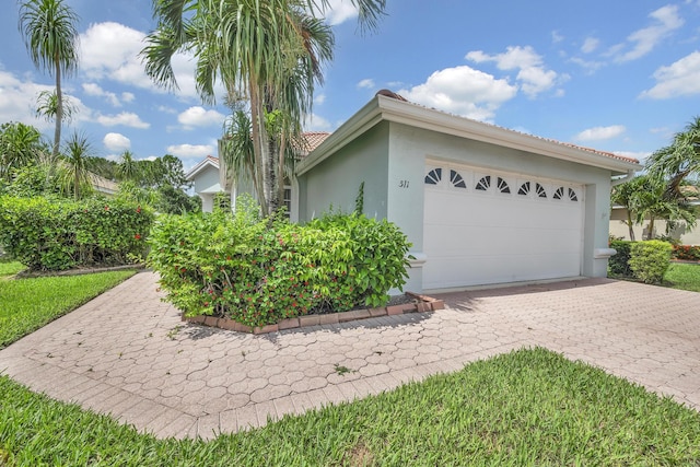 511 SW Treasure Cv, Port Saint Lucie, FL 34986 - view of home's exterior featuring stucco siding, a tiled roof, a garage, and driveway