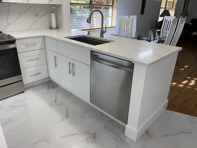 2975 SW 22nd Ave Unit 2010, Delray Beach, FL 33445 - kitchen featuring appliances with stainless steel finishes, light marble finish floors, light stone countertops, a peninsula, and white cabinets