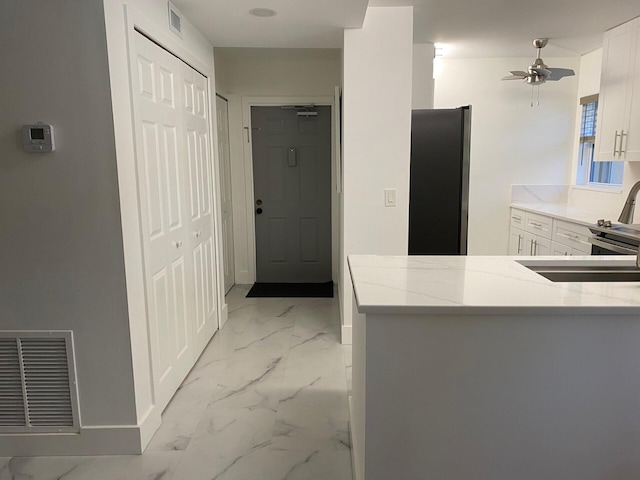2975 SW 22nd Ave Unit 2010, Delray Beach, FL 33445 - kitchen featuring freestanding refrigerator, light marble finish flooring, white cabinetry, and light stone counters