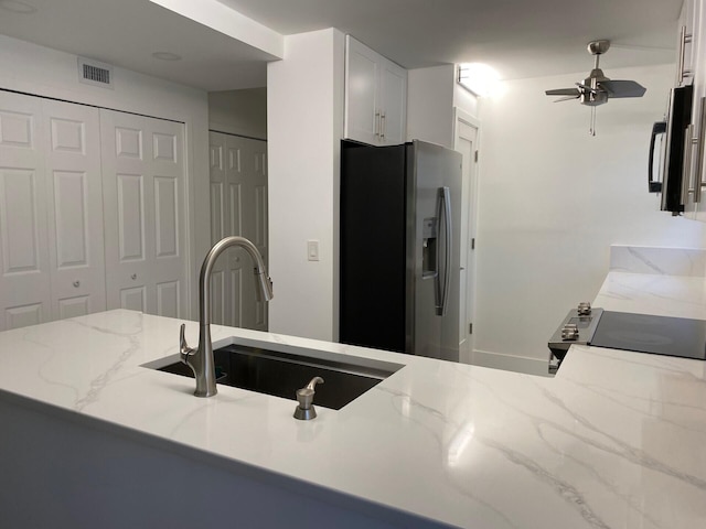 2975 SW 22nd Ave Unit 2010, Delray Beach, FL 33445 - kitchen with stainless steel fridge, ceiling fan, light stone counters, electric stove, and white cabinetry