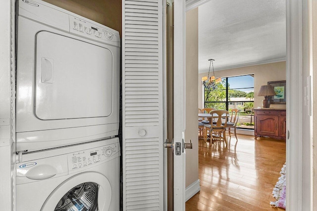 45 Stratford Ln Unit B, Boynton Beach, FL 33436 - laundry room featuring stacked washer / drying machine, crown molding, a chandelier, light wood-type flooring, and a textured ceiling