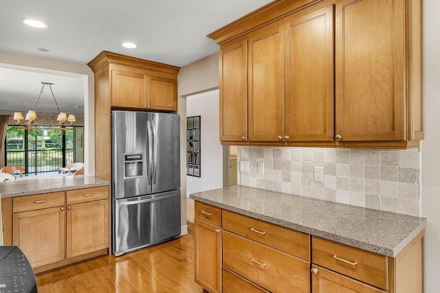 45 Stratford Ln Unit B, Boynton Beach, FL 33436 - kitchen featuring stainless steel fridge, light wood finished floors, tasteful backsplash, light stone counters, and brown cabinets