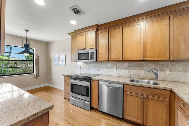 45 Stratford Ln Unit B, Boynton Beach, FL 33436 - kitchen with stainless steel appliances, brown cabinets, light wood-style flooring, decorative backsplash, and recessed lighting