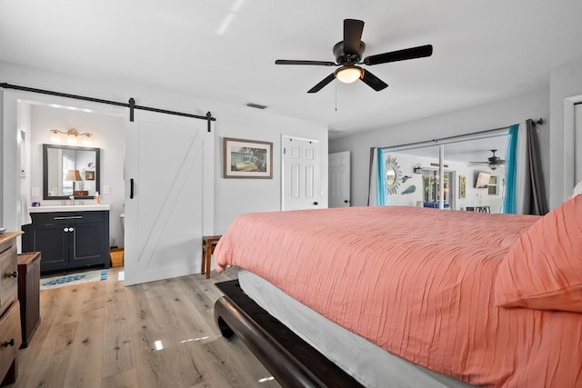 4931 SE Pompano Ter, Stuart, FL 34997 - bedroom featuring a barn door, light wood finished floors, access to exterior, connected bathroom, and a ceiling fan