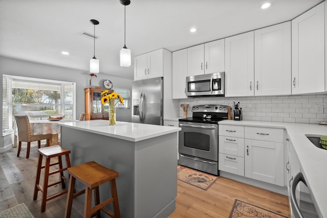 4931 SE Pompano Ter, Stuart, FL 34997 - kitchen featuring stainless steel appliances, a breakfast bar area, tasteful backsplash, light countertops, and recessed lighting
