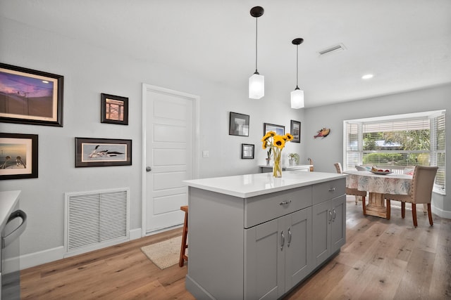 4931 SE Pompano Ter, Stuart, FL 34997 - kitchen featuring gray cabinets, light wood-type flooring, hanging light fixtures, light countertops, and a kitchen island