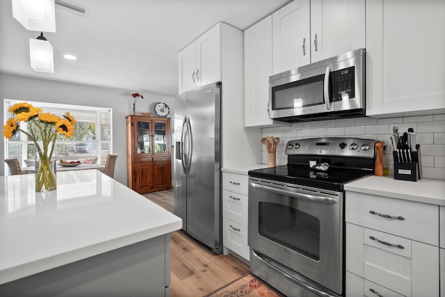 4931 SE Pompano Ter, Stuart, FL 34997 - kitchen featuring appliances with stainless steel finishes, light wood-style floors, tasteful backsplash, light countertops, and recessed lighting