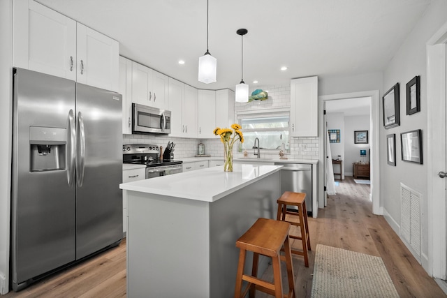 4931 SE Pompano Ter, Stuart, FL 34997 - kitchen with appliances with stainless steel finishes, a breakfast bar, backsplash, white cabinets, and recessed lighting