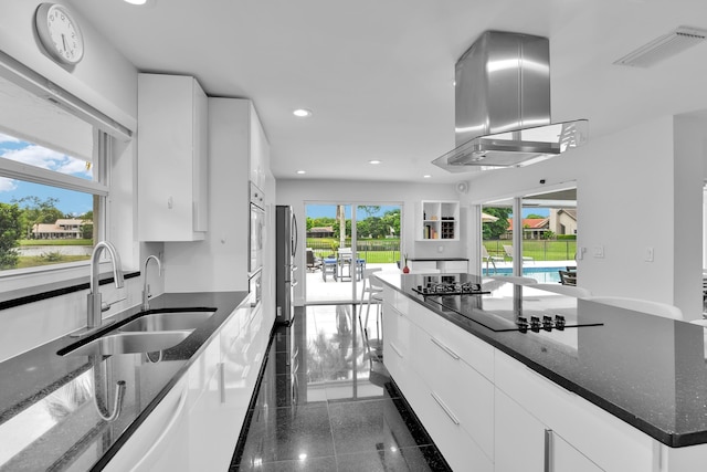 7197 Encina Ln, Boca Raton, FL 33433 - kitchen with island exhaust hood, recessed lighting, white cabinetry, granite floors, and dark stone counters